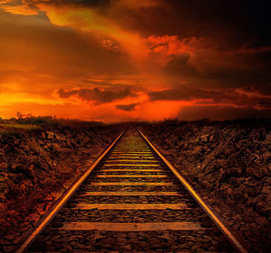 Railroad tracks against orange sky