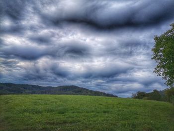 Scenic view of grassy field against cloudy sky