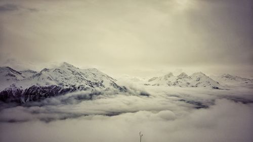 Scenic view of snow covered mountains against cloudy sky