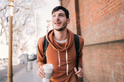 Young man holding coffee while standing outdoors