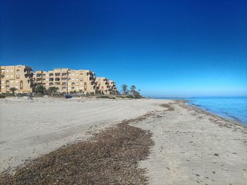 Scenic view of beach against clear blue sky