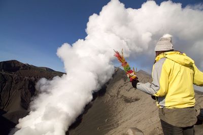 Rear view of woman standing on volcano against sky
