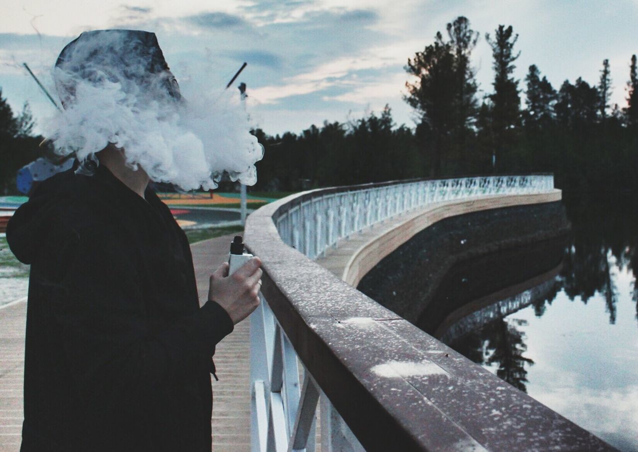 lifestyles, leisure activity, winter, water, sky, railing, men, part of, cold temperature, holding, person, snow, personal perspective, cropped, lake, tree, season