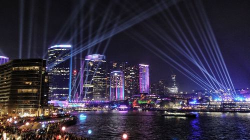 Illuminated buildings by river at night
