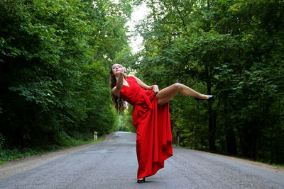 Woman standing by road against trees