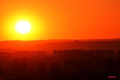 Scenic view of silhouette landscape against orange sky