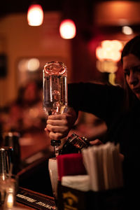 Reflection of man drinking glass on table at bar