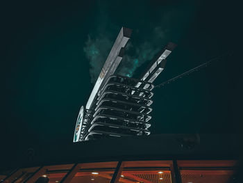 Low angle view of illuminated industry against sky at night