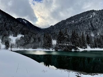 Scenic view of lake by snowcapped mountains against sky