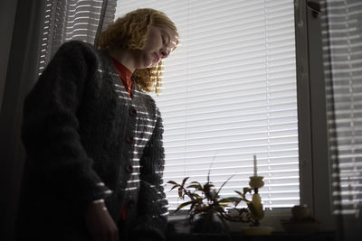 Pensive teenage girl looking through window