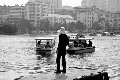 Rear view of man and woman standing on boat in city