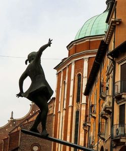 Woman jumping statue against sky in city