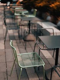 Empty chairs and tables at sidewalk cafe