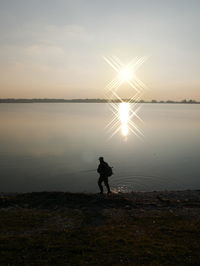 Silhouette man fishing at calm sea