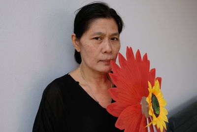 Portrait of mature woman with floral patterned pinwheel toy at home