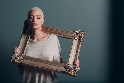 Young woman with picture frame against colored background