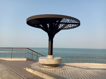 Railing by sea against clear sky