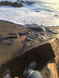 Low section of man standing on wet shore