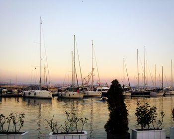 Sailboats moored on sea against clear sky during sunset