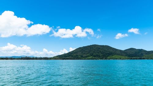 Scenic view of sea by mountain against sky