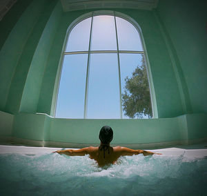 Man relaxing in swimming pool against window