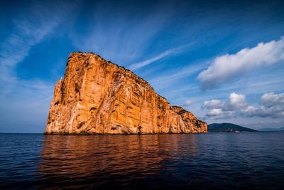 Rock formations by sea against blue sky