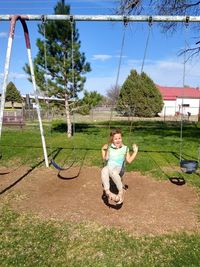 Full length of man sitting on swing in field