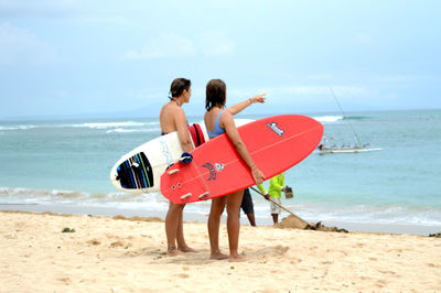 Women standing with surfboards on beach