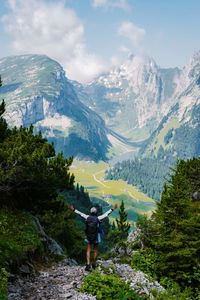 Rear view of man standing by mountains against sky