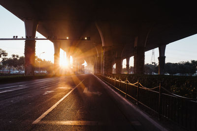 Bridge over highway against sky during sunset