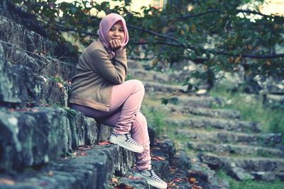 Portrait of smiling young woman sitting on land