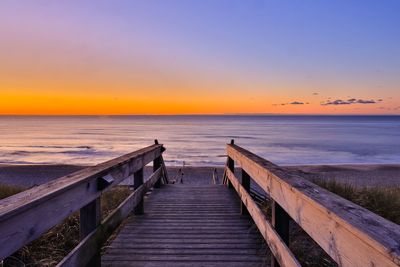 Pier over sea against sky during sunset