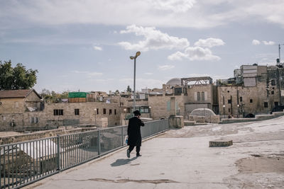 Rear view of man walking on buildings in city