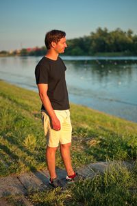 Portrait of mature man standing on lake shore during sunset