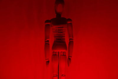 Close-up of wooden figurine against red wall
