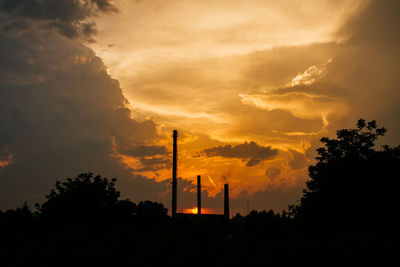 Low angle view of silhouette factory against sky during sunset