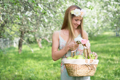 Woman wearing flowers while holding basket at park