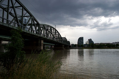 Bridge over river in city against sky