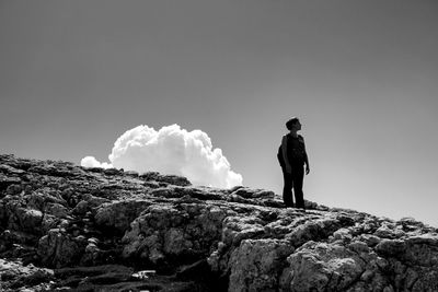 Rear view of man standing on rock against sky