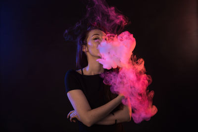 Portrait of young man smoking against black background