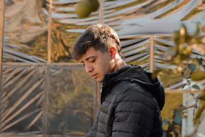 Young man looking away while standing outdoors