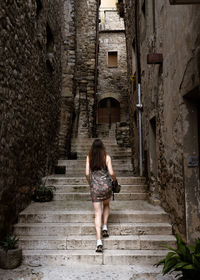 Rear view of woman walking on staircase amidst buildings