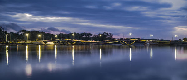 Illuminated bridge over river against sky at night