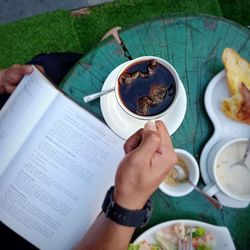 High angle view of hand holding coffee cup on table