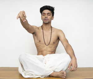 Portrait of young man sitting against wall