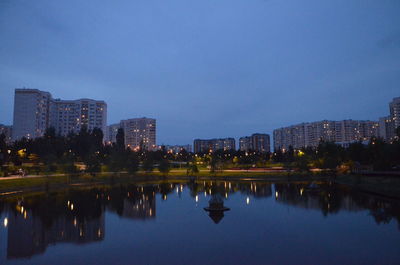 Reflection of buildings in lake against sky in city