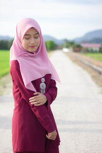 Young woman in hijab standing on footpath against sky