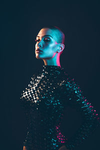 Young woman with shaved head against black background