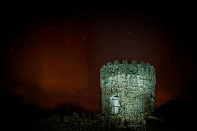 Illuminated built structure against sky at night