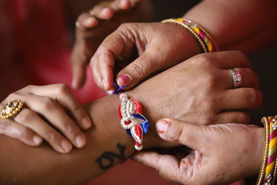 Cropped hands of sister tying rakhi of hand of brother